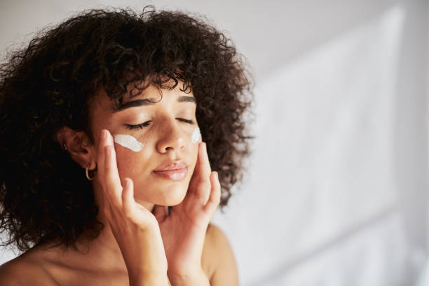 A woman applying skincare cream to her face, highlighting a step in caring for combination skin.